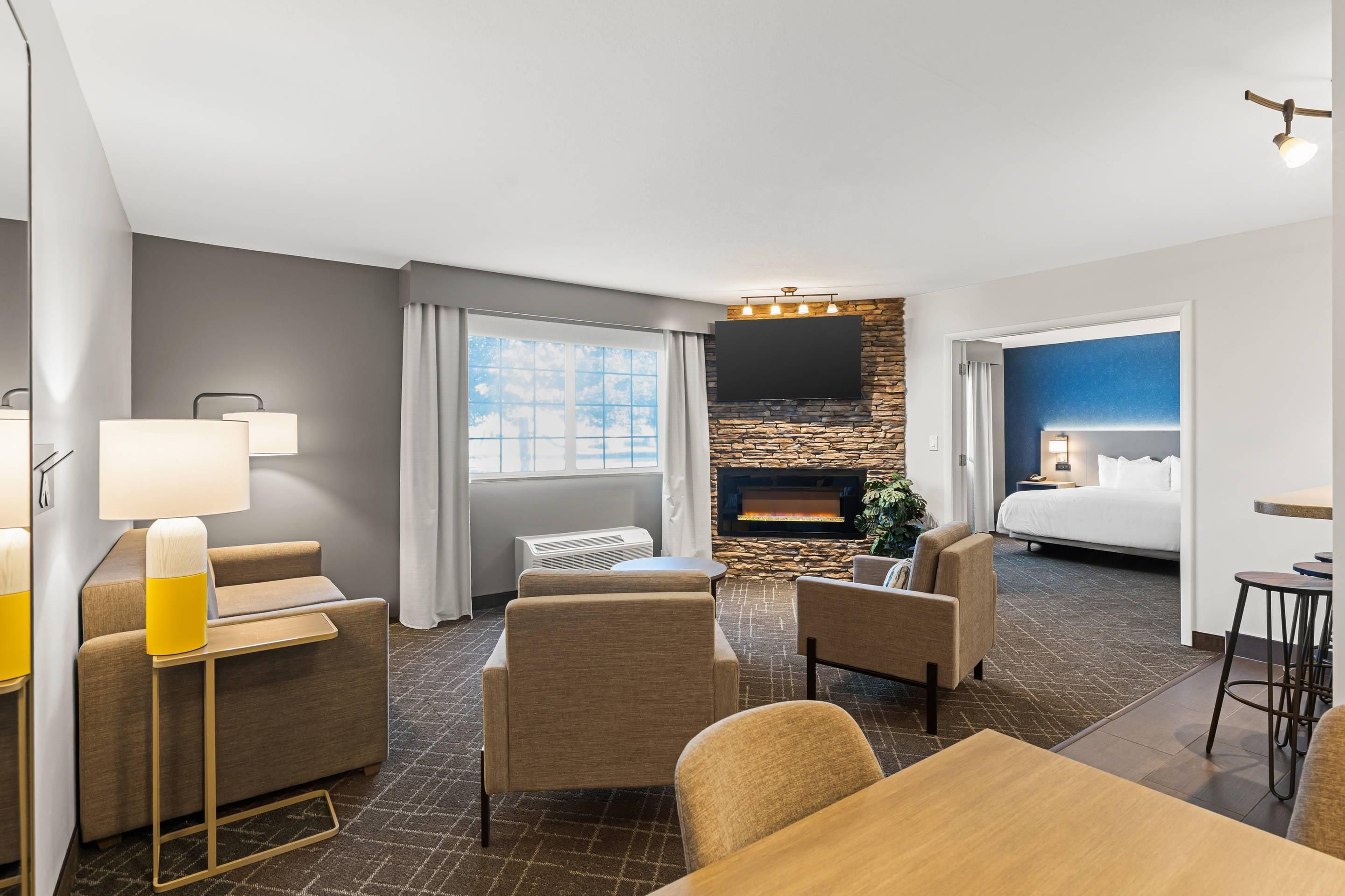 A hotel room with a fireplace, a bed, a desk, and a seating area.