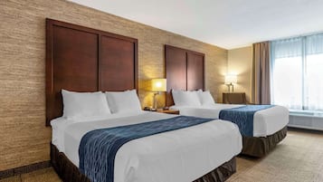 Ett hotellrum med två sängar, ett stort fönster med gardiner, en vägglampa och en vägg med en intressant yta.