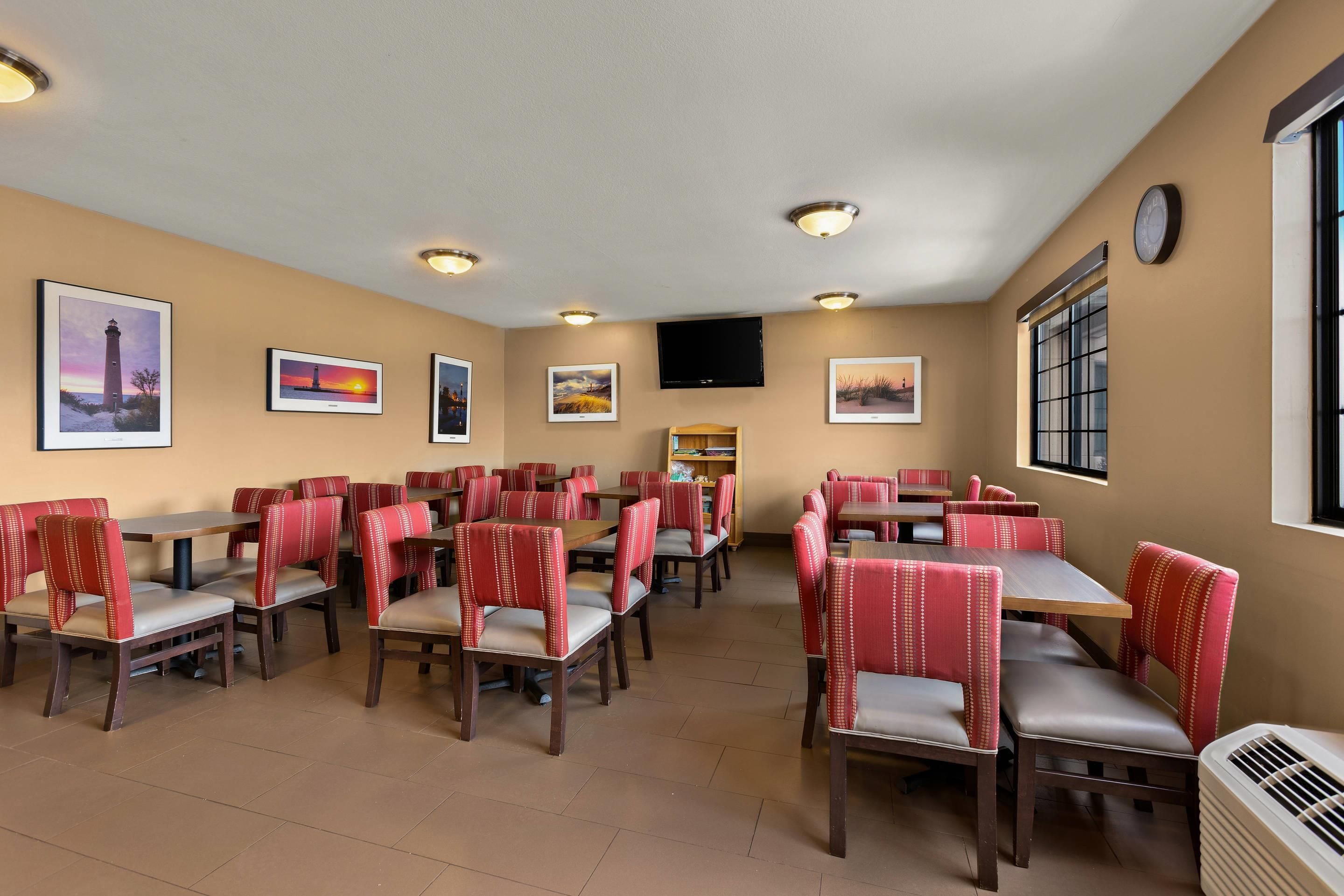 A restaurant with multiple tables and chairs, ceiling lights, and wall-mounted artwork.
