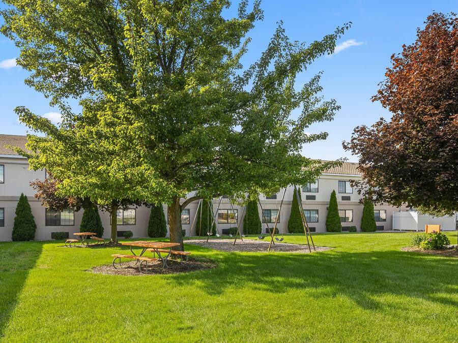 A courtyard with a lawn, picnic tables, and swings.