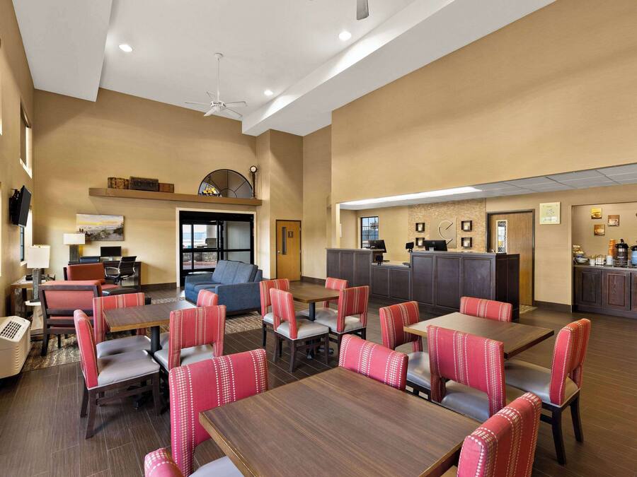 A hotel lobby with multiple seating areas, a reception desk, and a kitchen area.