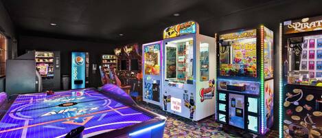 A room with arcade games, a pool table, and a colorful carpet.
