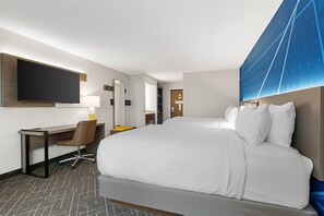 A hotel room with a large bed, a desk, a chair, a flat-screen TV, and a large window with a view of a building. - Comfort Inn & Suites Ludington near US-10 (Ludington)