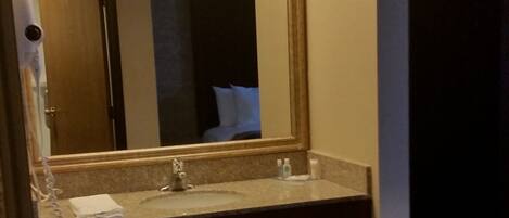 A bathroom with a large mirror, two sinks, a towel rack, and a hairdryer.