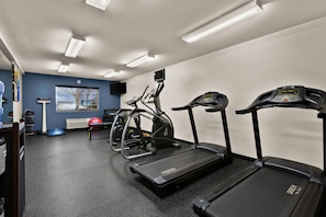 Une salle de sport équipée de tapis de course, d’appareils d’entraînement elliptique et d’un vélo d’appartement.