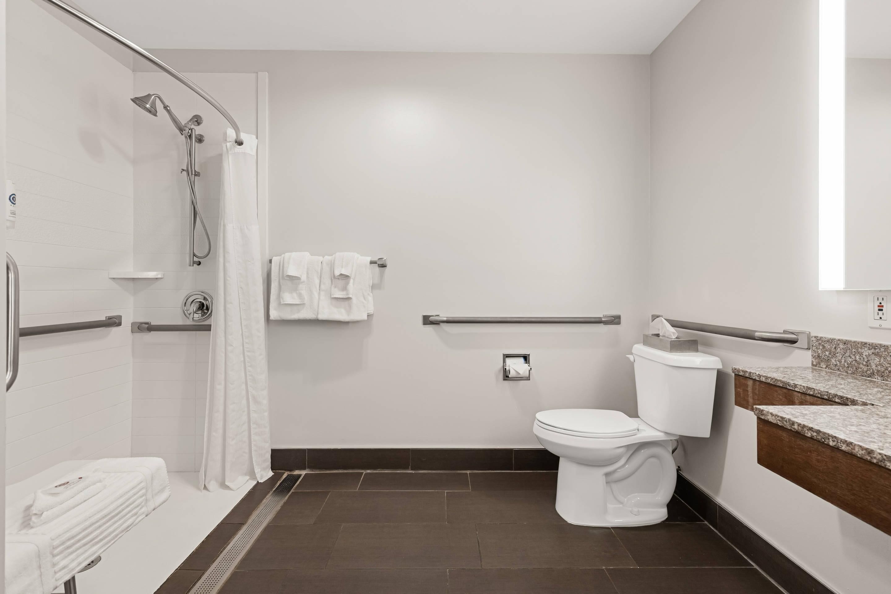 A modern bathroom with a shower, toilet, and a towel rack.