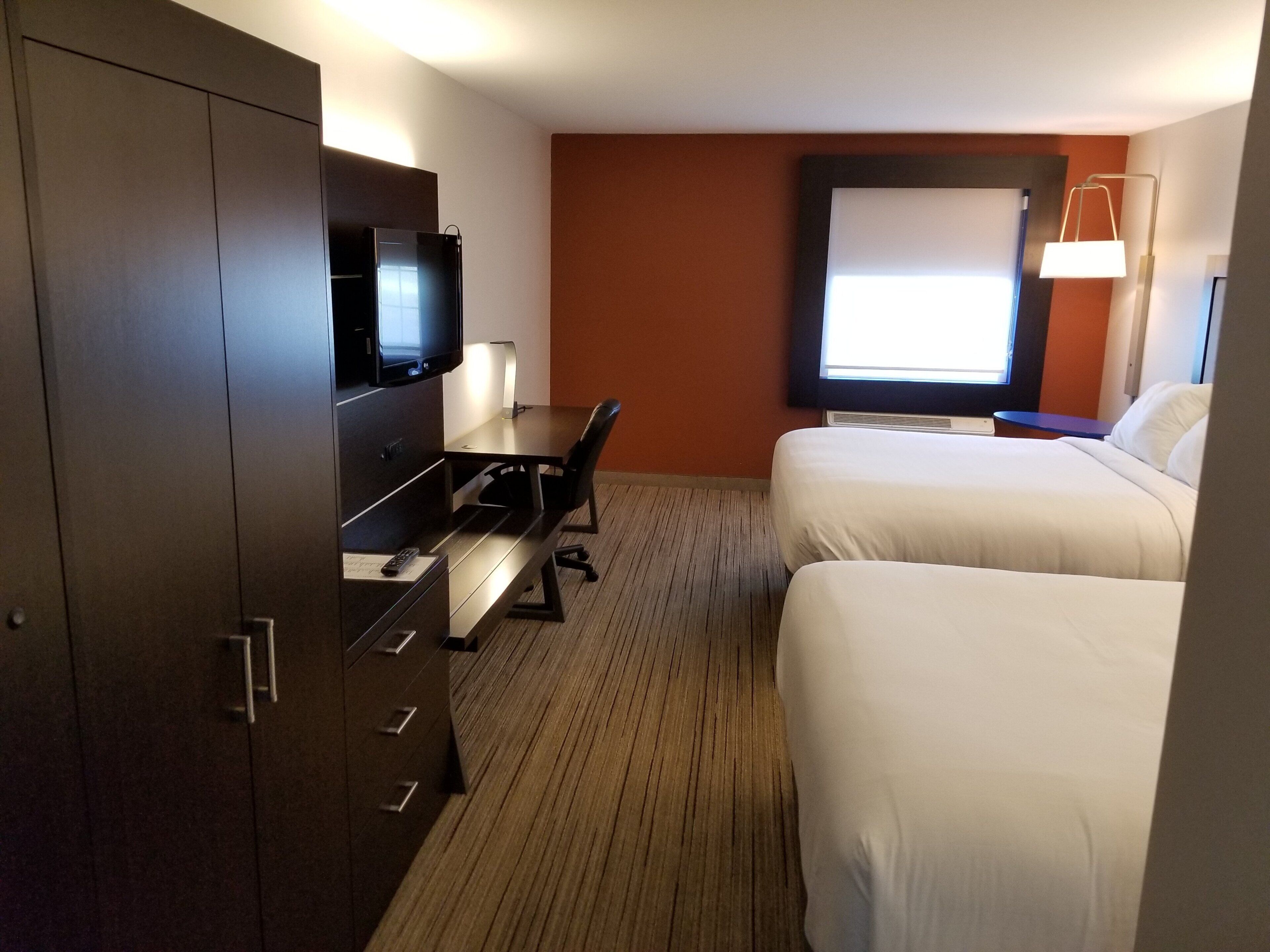Een hotelkamer met een bed, een bureau, een televisie en een raam.