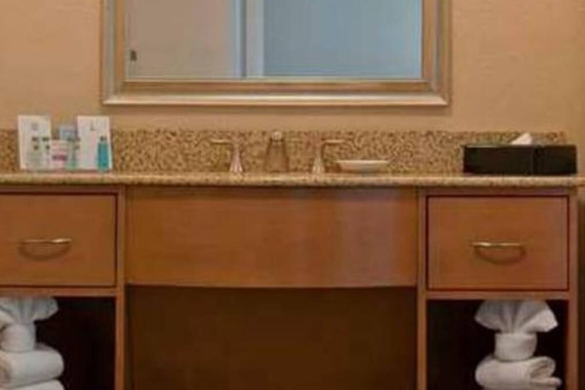 A bathroom with a sink, mirror, and two towel racks.