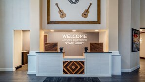 A reception area with a welcome sign, two guitars, and a geometric patterned panel.