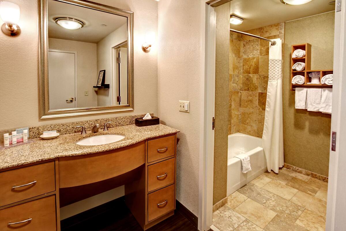 A bathroom with a sink, mirror, and shower.