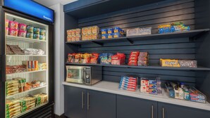 A refrigerated section with various frozen food items and a microwave. - Spark by Hilton Bakersfield Central (Bakersfield)