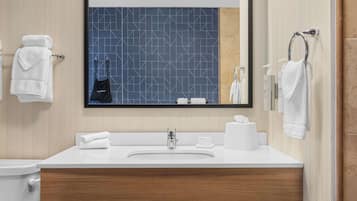 A modern bathroom with a large mirror, white sink, and wooden vanity.