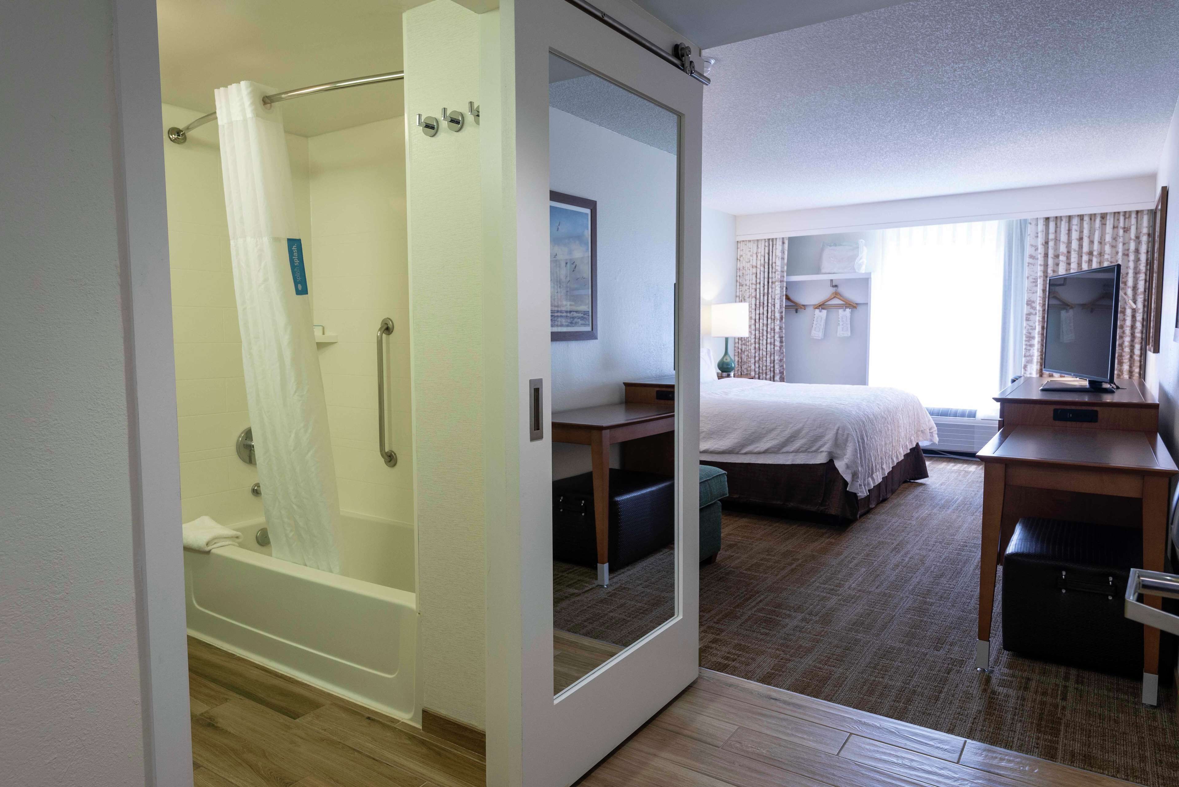 Une chambre d’hôtel équipée d’une douche, d’un lit, d’un bureau et d’un téléviseur.