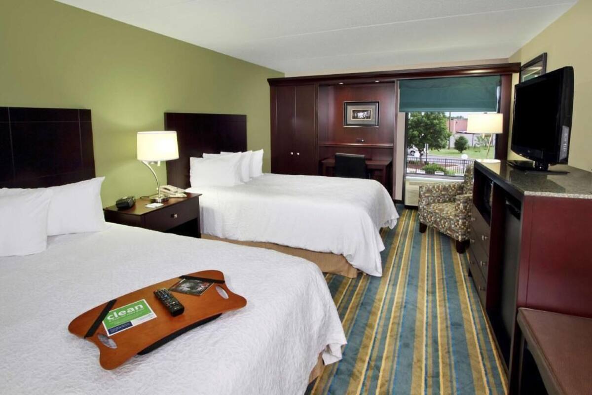 Habitación de hotel con dos camas, un escritorio, un televisor y vistas al exterior.
