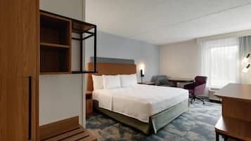 Una habitación de hotel con una cama grande, un escritorio, una silla, un armario y una ventana con cortinas.