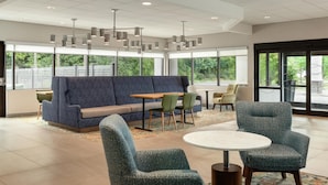 A modern lobby with a blue sofa, round tables, and green chairs. - Hampton Inn Hagerstown (Hagerstown)