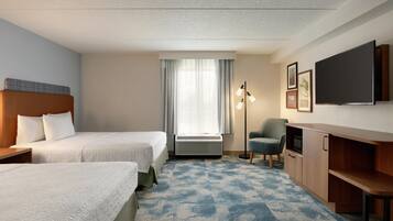 A hotel room with two beds, a desk, a chair, a flat-screen TV, and a large window with curtains.