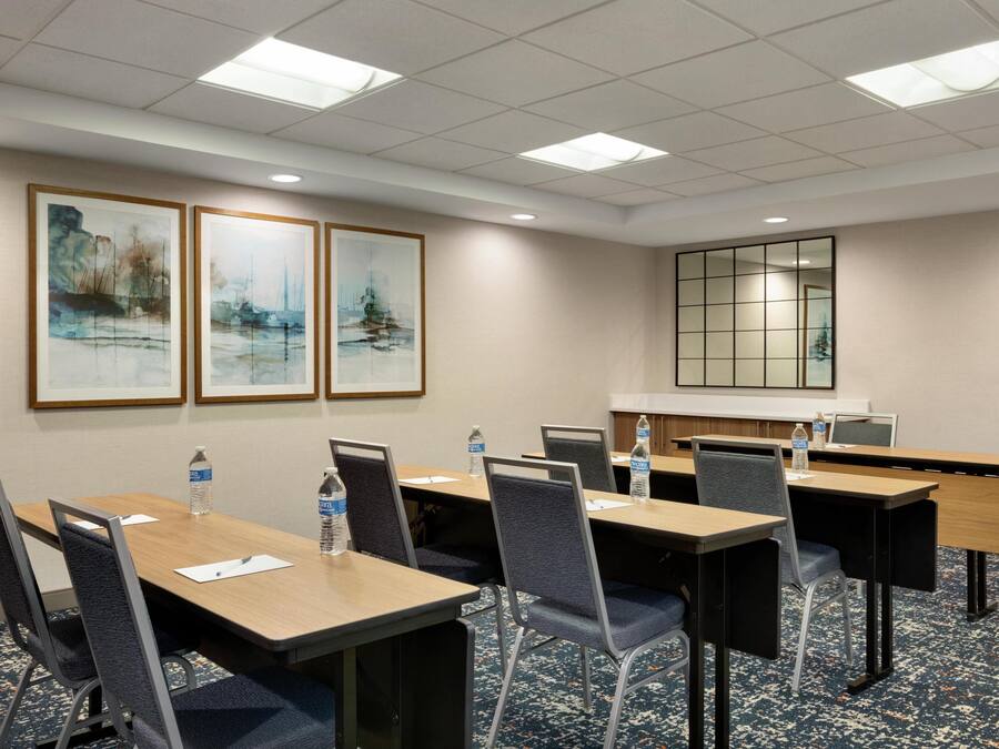 A conference room with tables, chairs, framed artwork on the wall, and a large window.