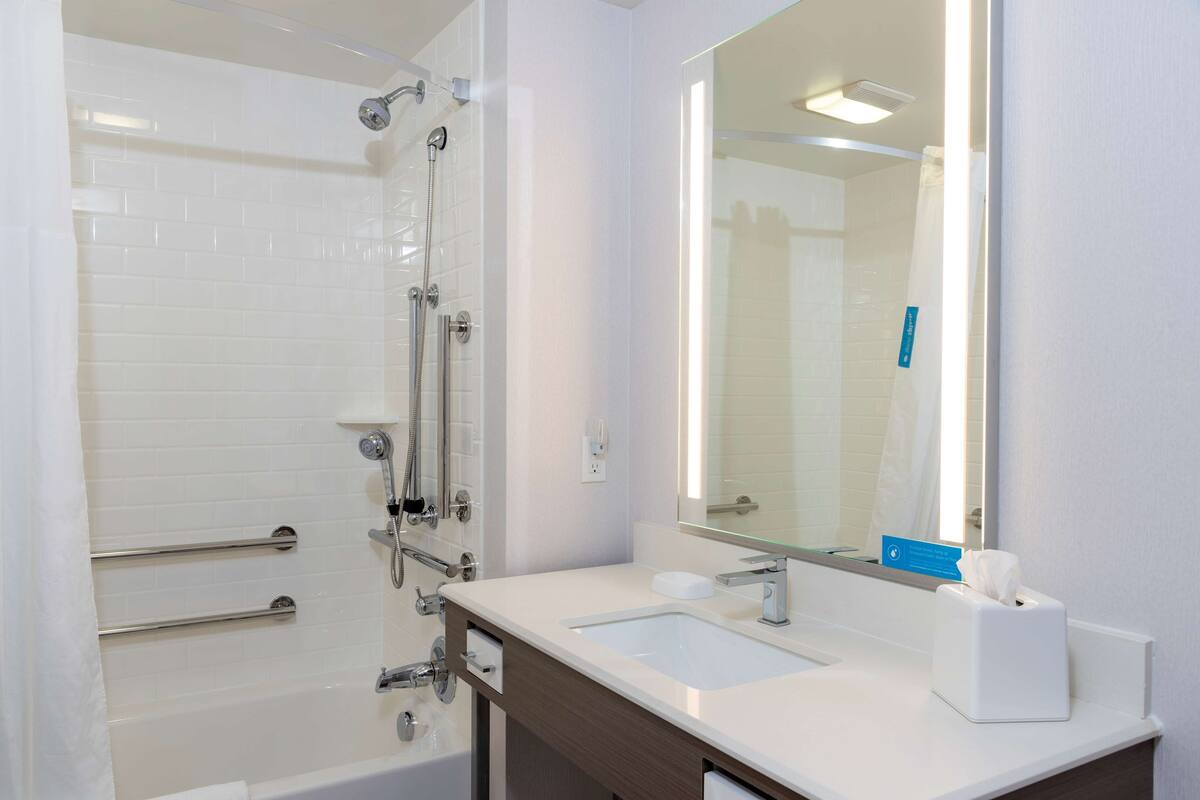 A modern bathroom with a bathtub, shower, and sink.