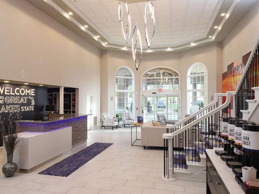 A hotel lobby with a reception desk, seating area, and a staircase.
