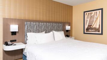 Habitación de hotel con una cama grande, dos mesitas de noche con lámparas, un teléfono y un cuadro enmarcado en la pared.