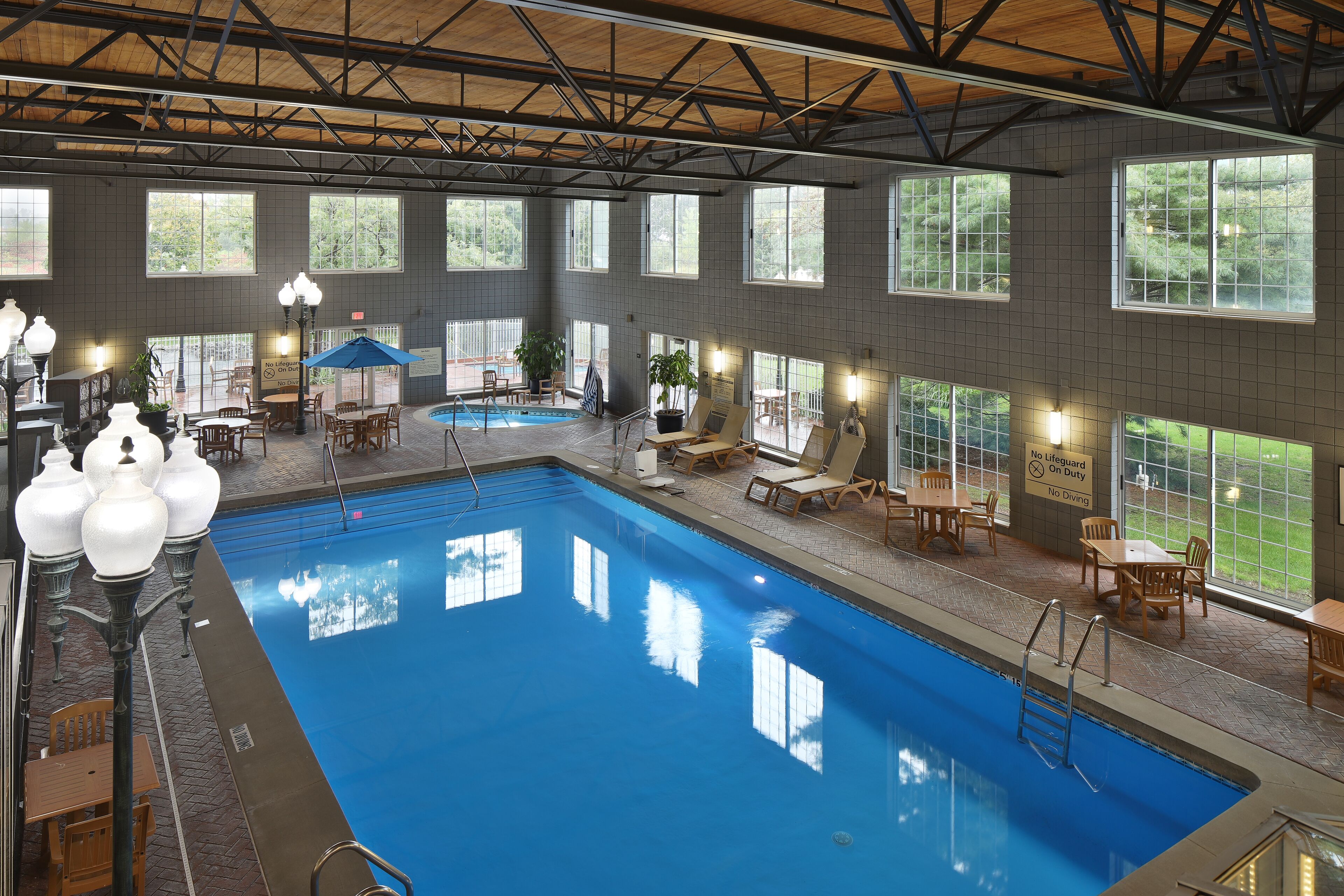 An indoor swimming pool with a clear view of the pool area, including the pool, surrounding lounge chairs, and a sign indicating no diving.
