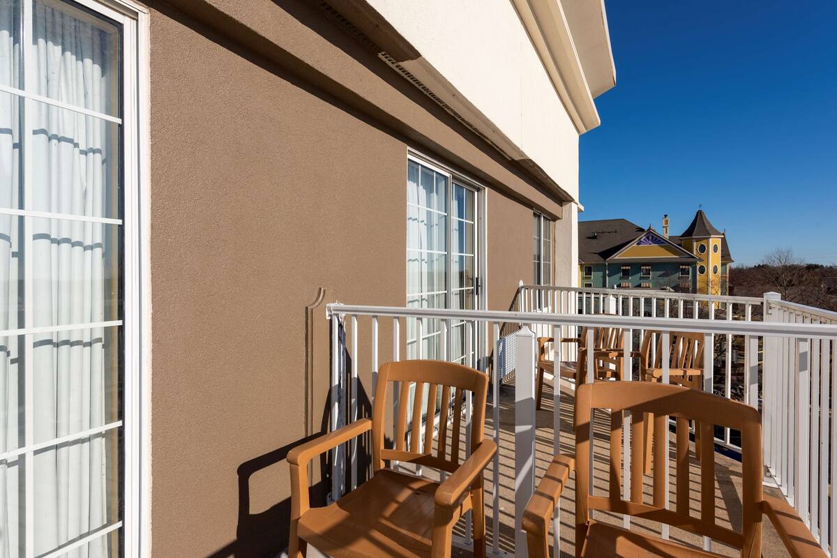 A balcony with wooden chairs and a railing.