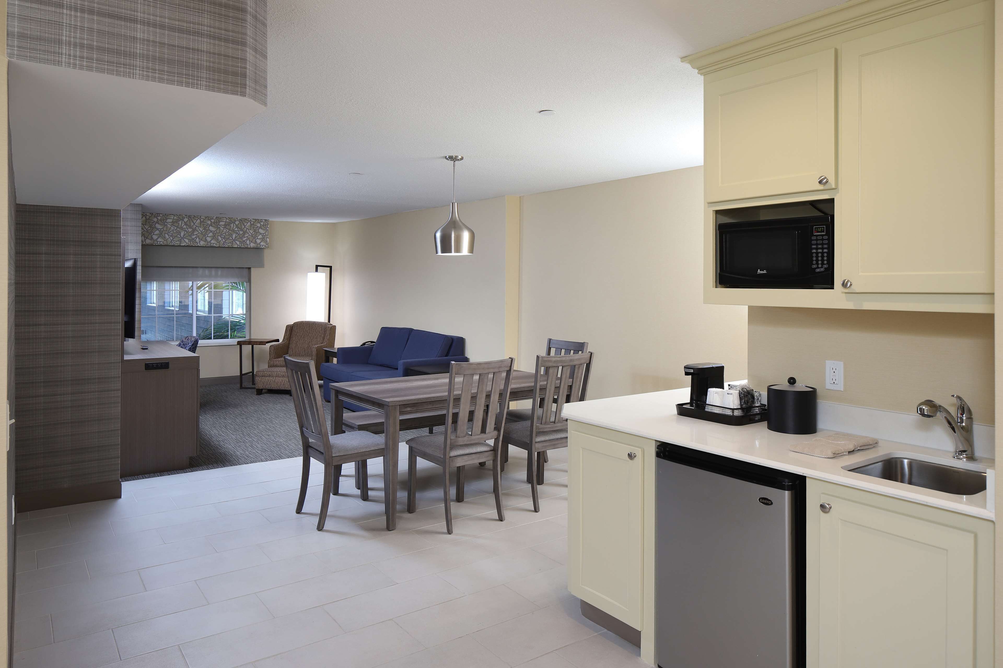A compact kitchen with a microwave, sink, and a dining area with chairs and a table.