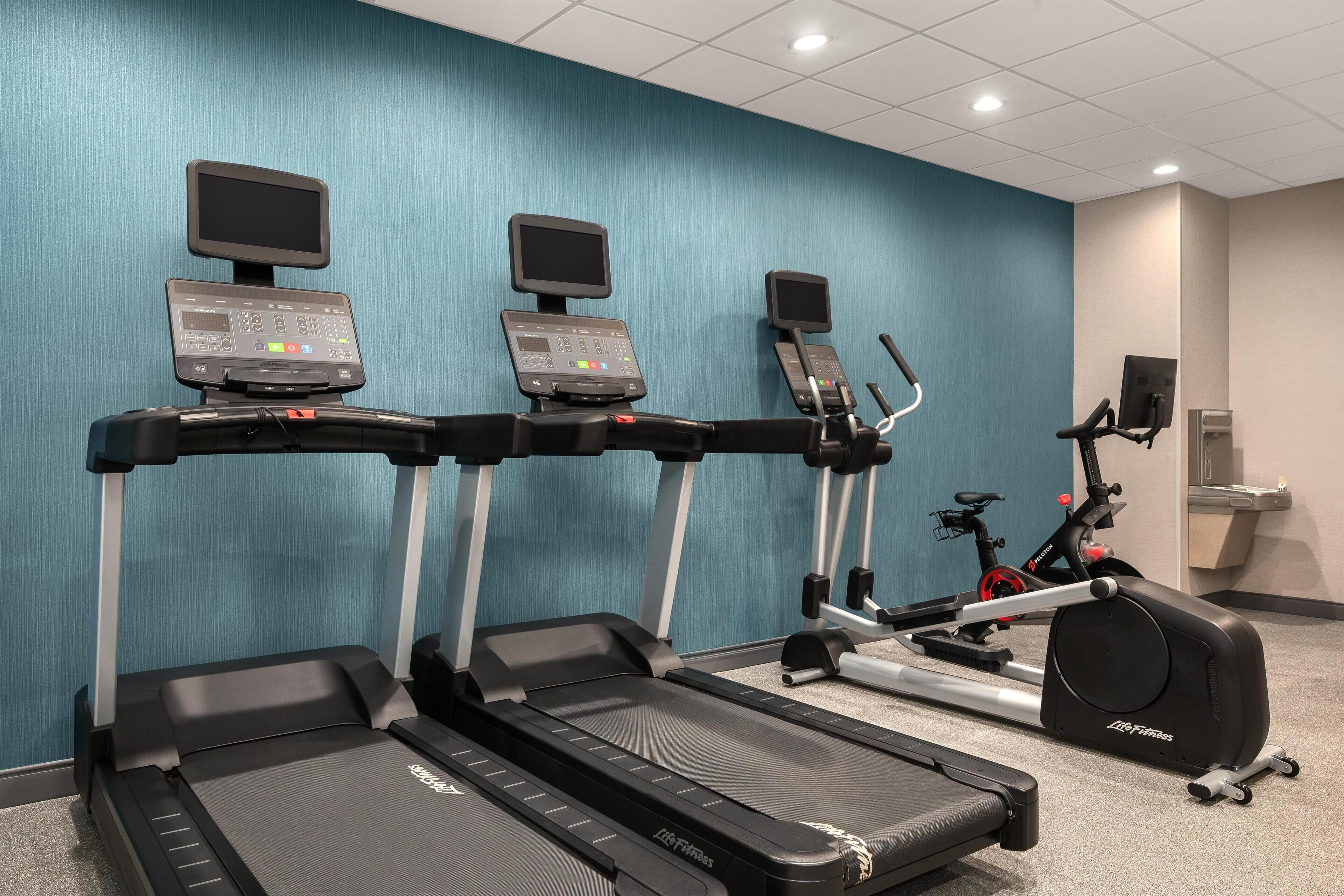 A fitness area with treadmills, a stationary bike, and a rowing machine.