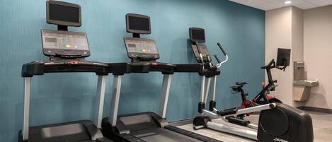A fitness area with treadmills, a stationary bike, and a rowing machine.