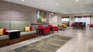 A modern lobby with seating areas, a mural, and a dining setup.