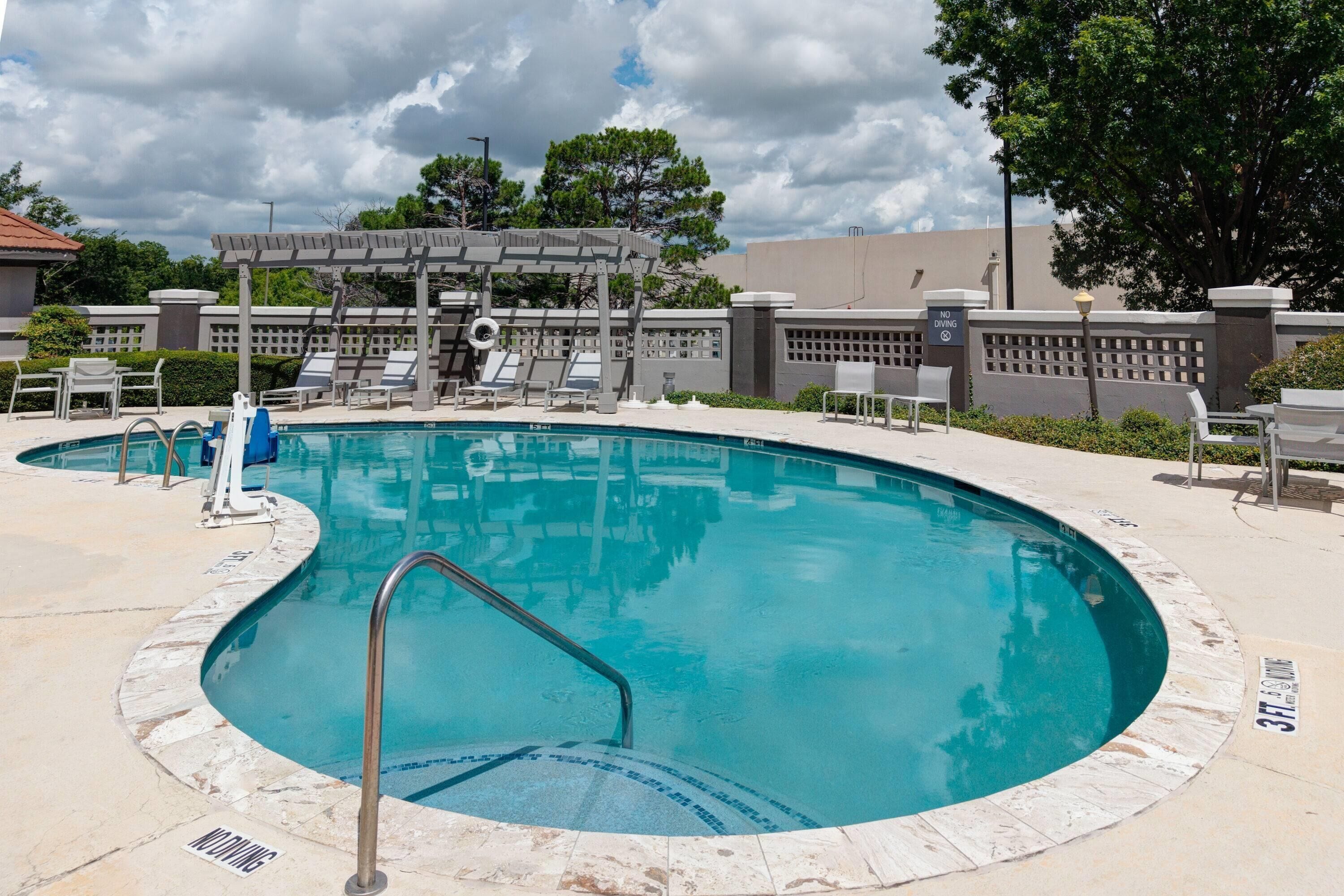 Piscina com pergolado, espreguiçadeiras e placa de proibição de saltos.