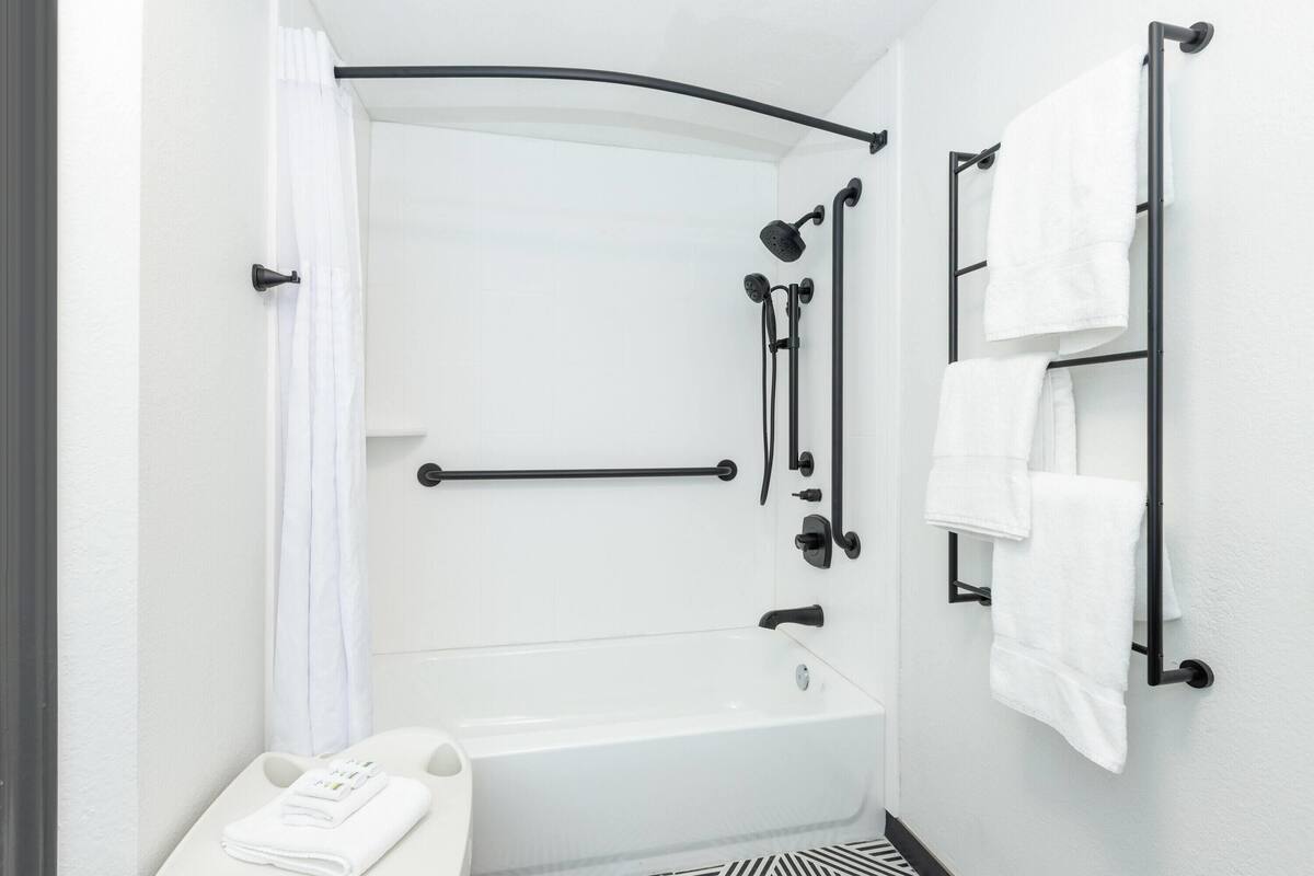 A modern bathroom with a white bathtub, black towel rack, and a towel warmer.