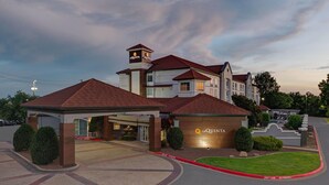 A hotel with a prominent tower, multiple entry points, and a well-maintained lawn. - La Quinta Inn & Suites by Wyndham Sherman (Sherman)