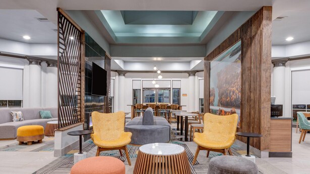 A modern lobby with seating areas, a reception desk, and a large window. - La Quinta Inn & Suites by Wyndham Sherman (Sherman)