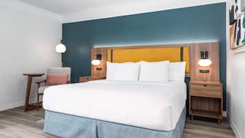 Ein Hotelzimmer mit einem großen Bett, zwei Nachttischen, einem Sessel und einem Beistelltisch.