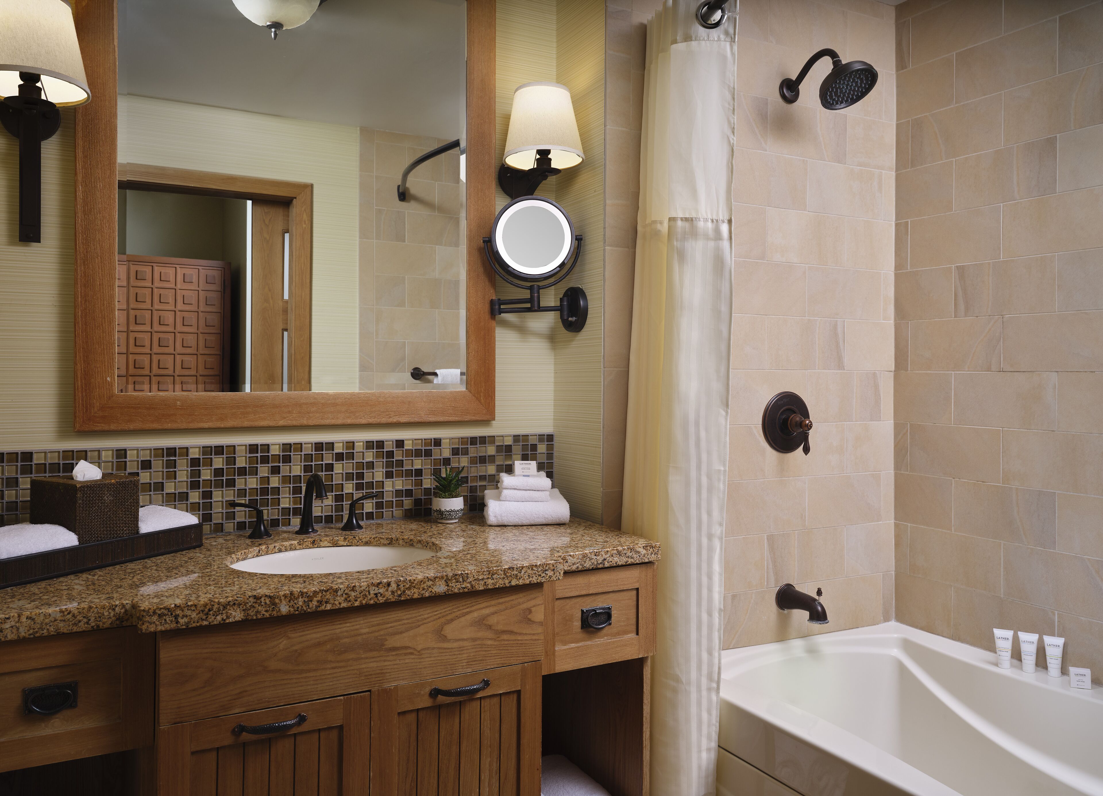 A bathroom with a wooden vanity, a large mirror, a shower with a curtain, and a bathtub.