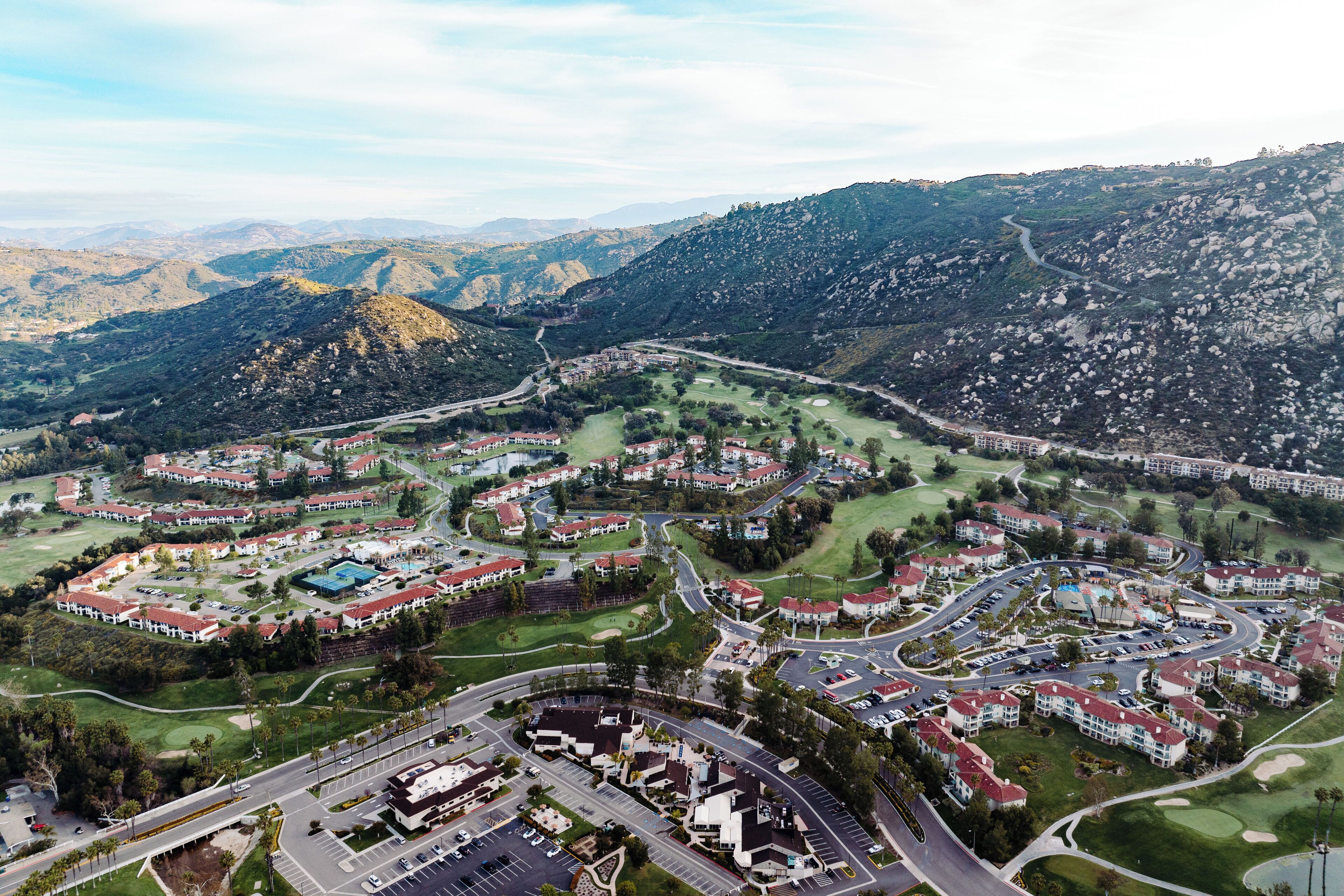 An aerial view of a residential area with houses, roads, and a golf course.