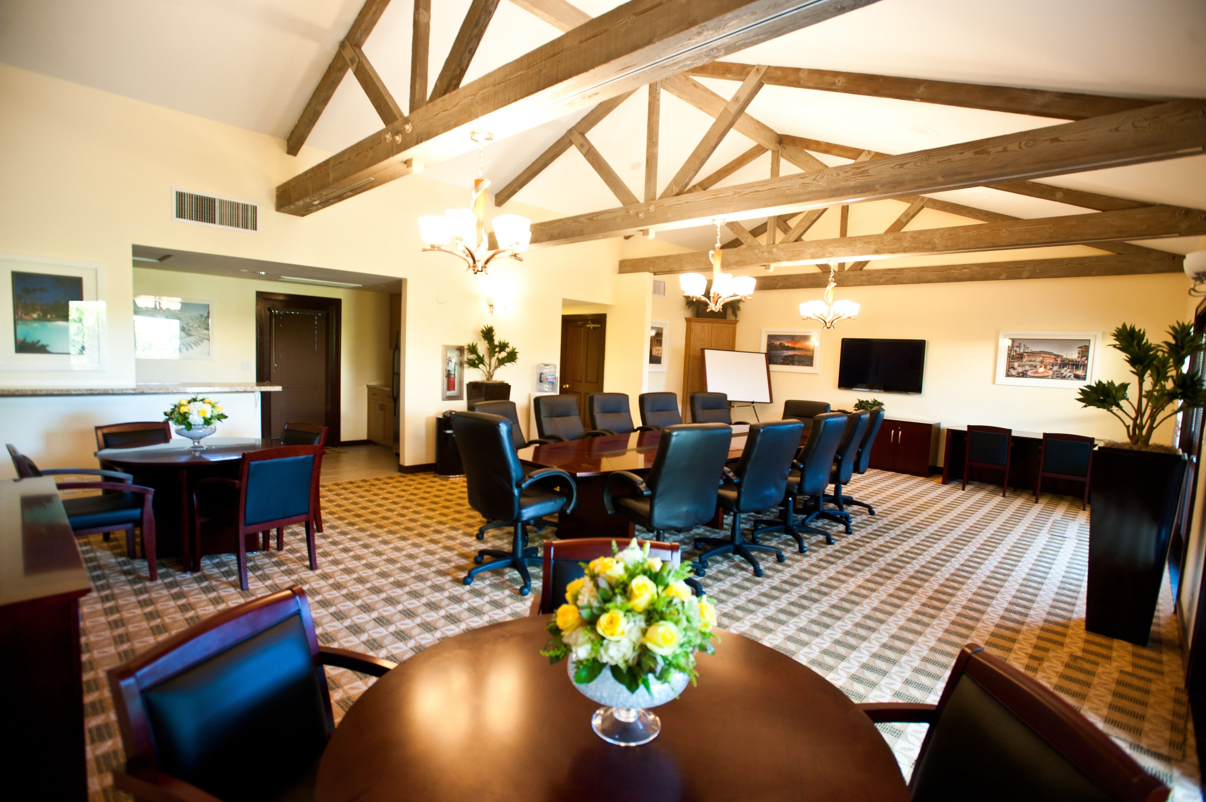 A conference room with a large table, multiple chairs, and a chandelier.