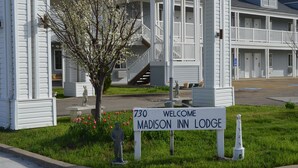 A white building with a sign reading "730 Welcome Madison Inn Lodge" and a small tree in front.