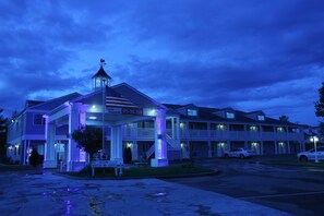A motel with a covered entrance, a flag, and a phone number.