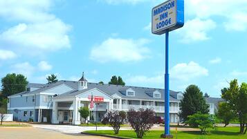 Un motel de dos pisos con un cartel que anuncia 'Madison Inn Lodge' y un letrero que indica 'Nueva Administración'.