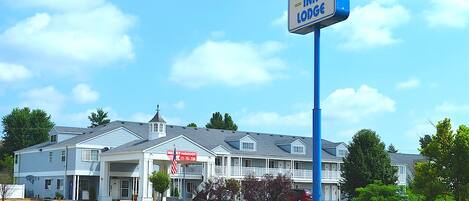 Un motel de dos pisos con un cartel que anuncia 'Madison Inn Lodge' y un letrero que indica 'Nueva Administración'.