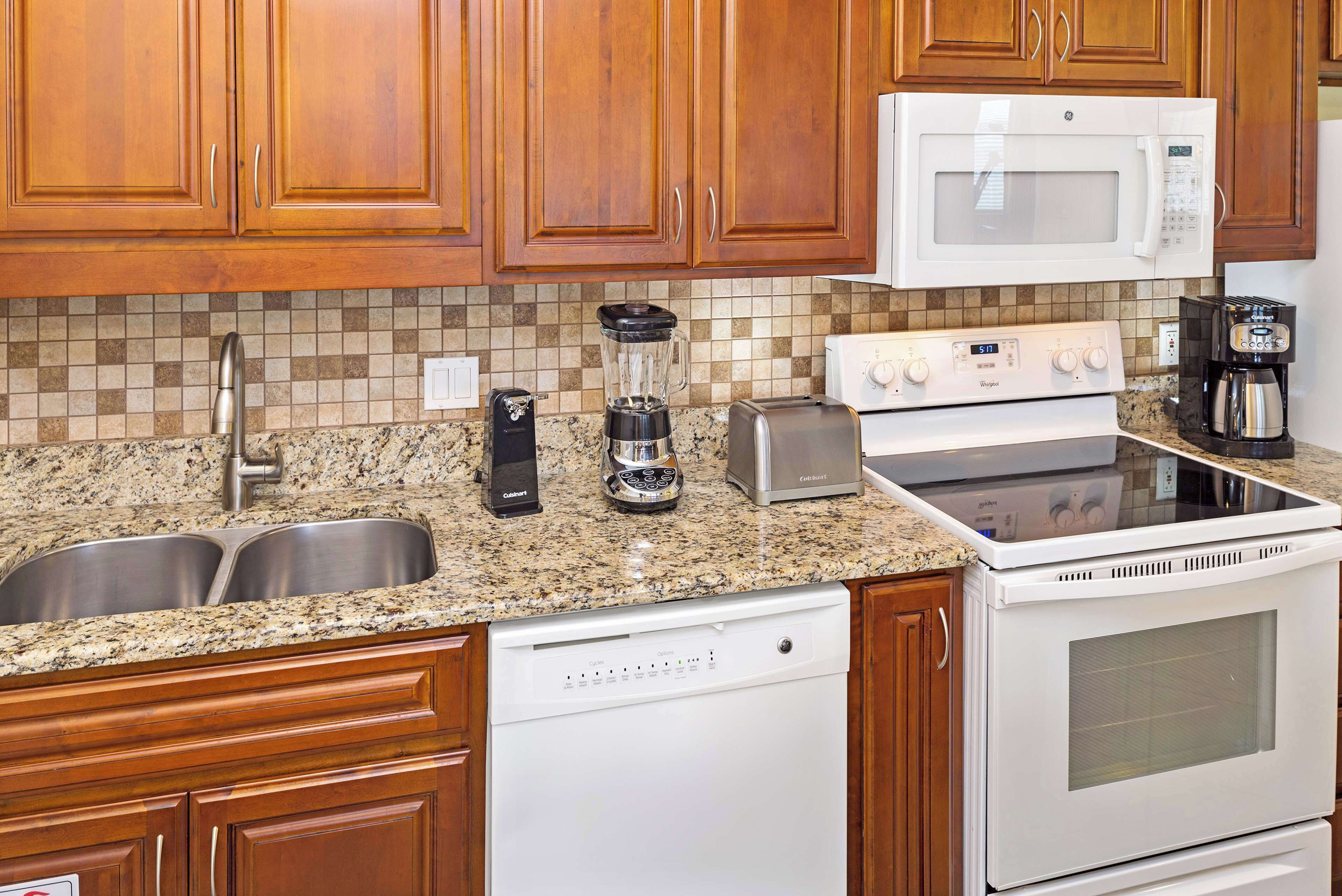 A kitchen with wooden cabinets, a granite countertop, stainless steel sink, a coffee maker, a toaster, and a dishwasher.