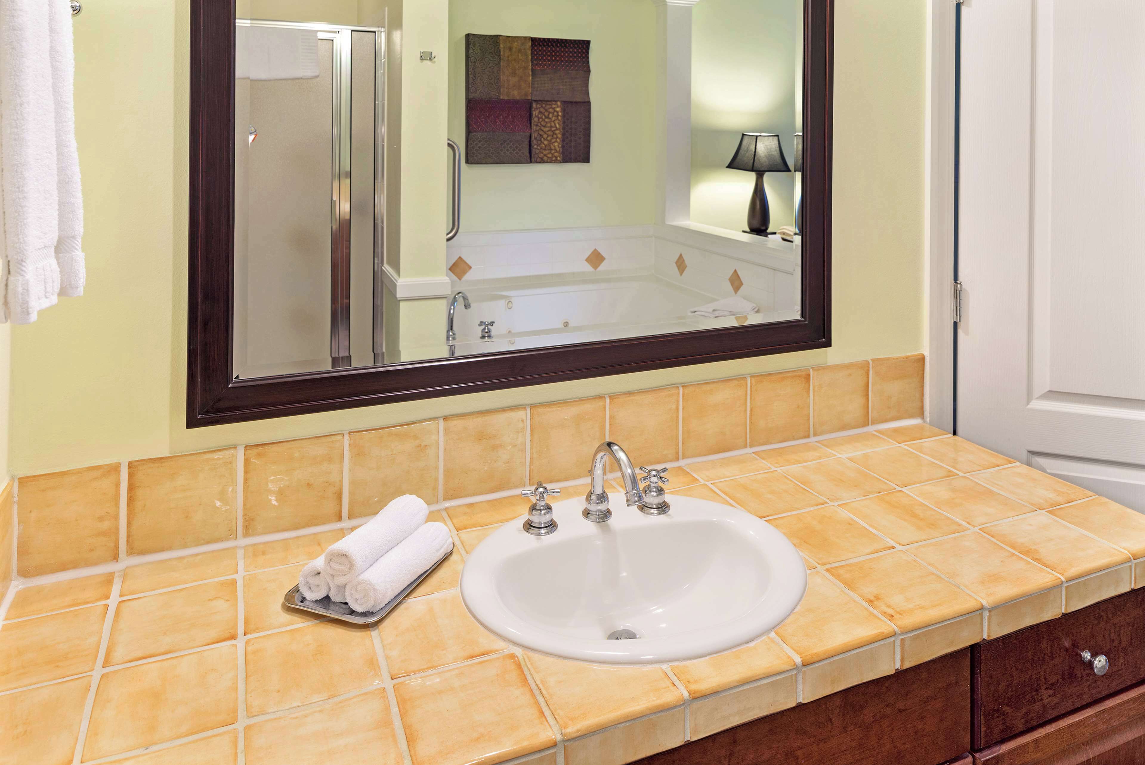 Un baño con un lavamanos blanco, un espejo y un toallero.