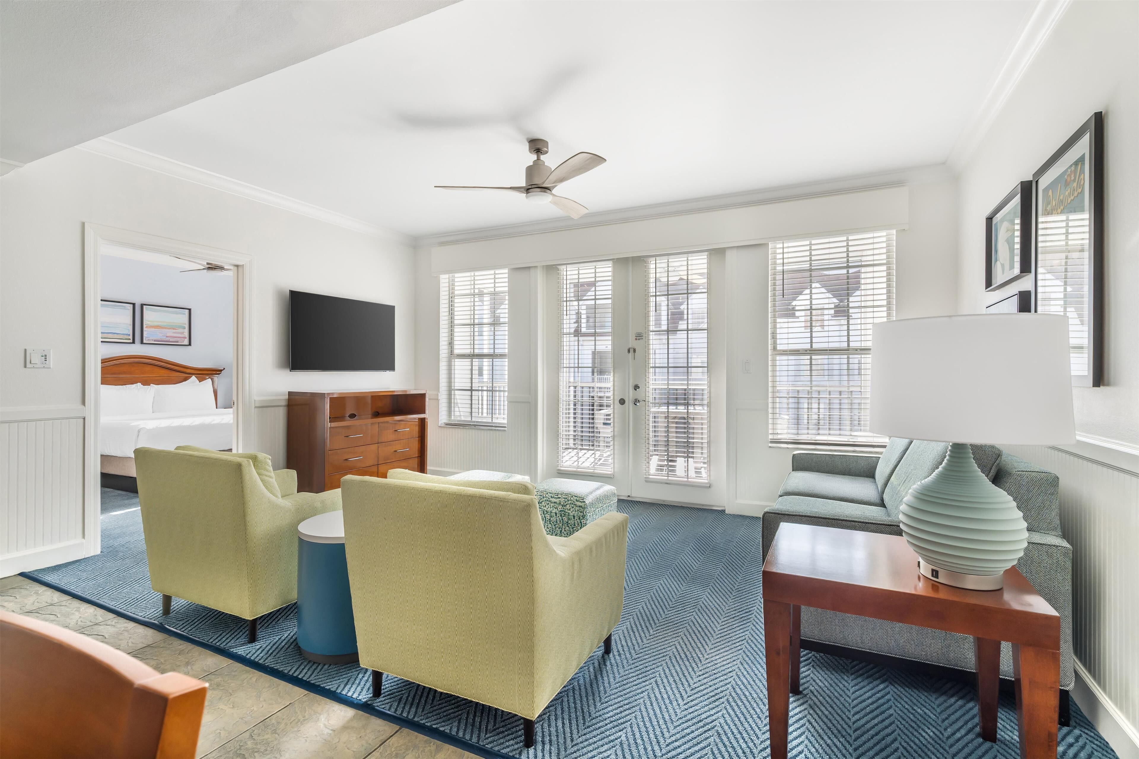 Un salon moderne avec un ventilateur de plafond, un canapé, une table basse et un téléviseur.