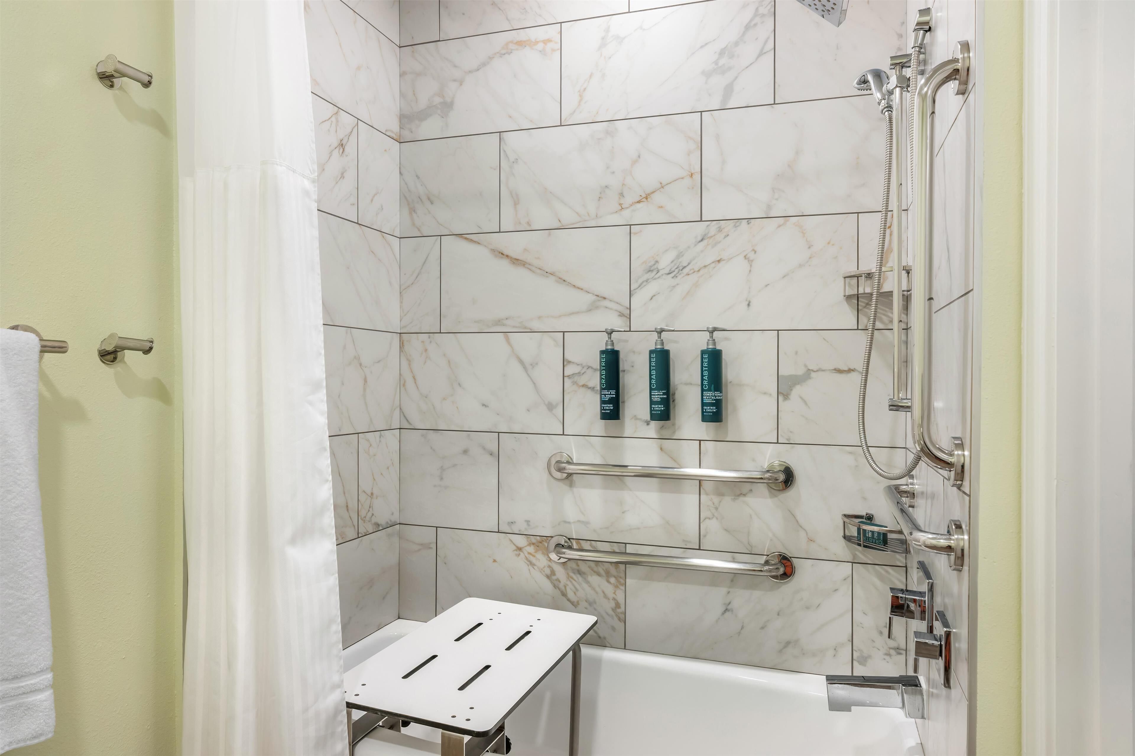 A bathroom with a shower, a bathtub, and a small step stool.