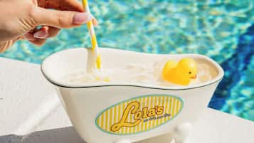 Una bañera con un patito amarillo y una pajita a rayas, al lado de una piscina.