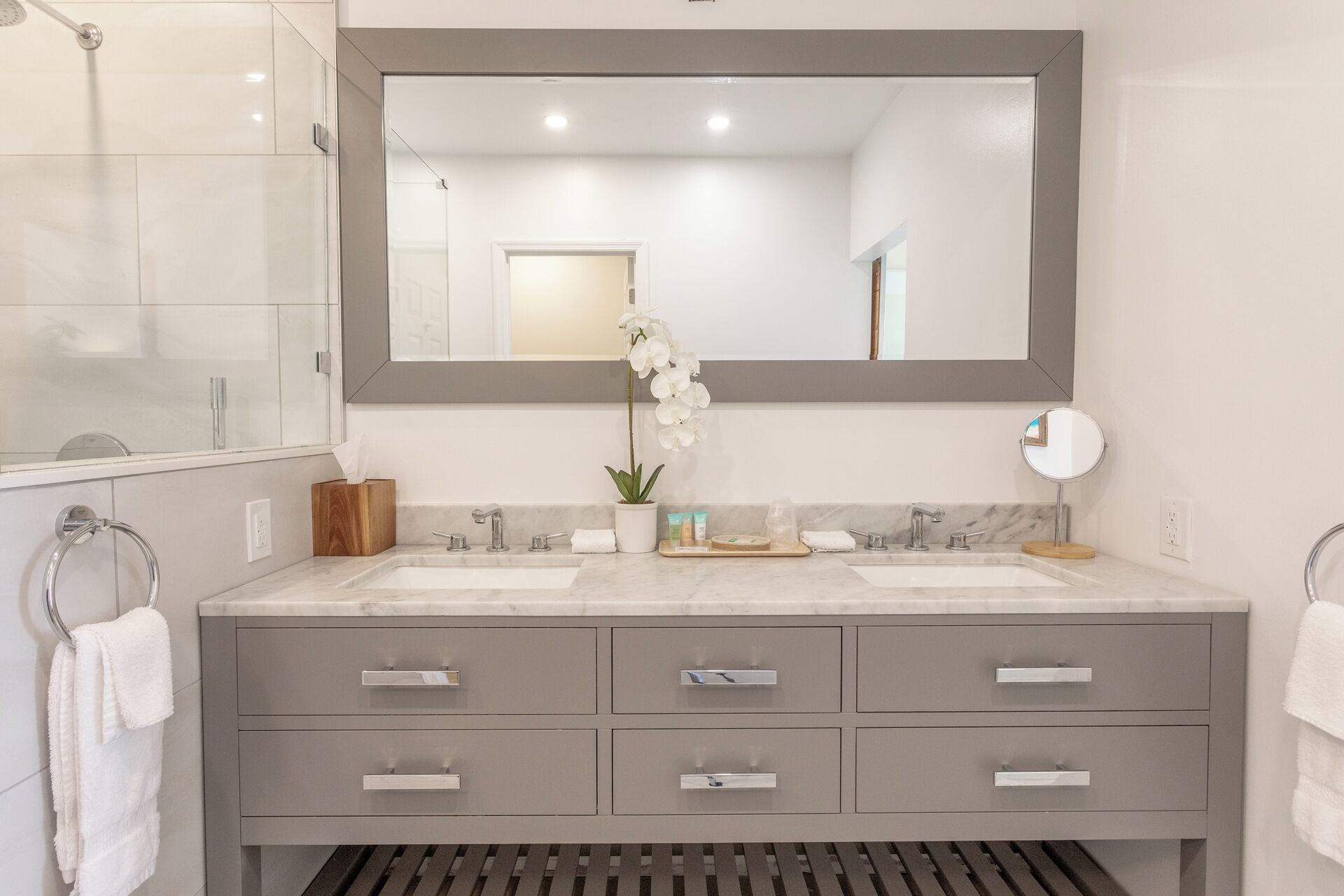 Un baño moderno con dos lavamanos, un espejo grande y una orquídea en maceta.