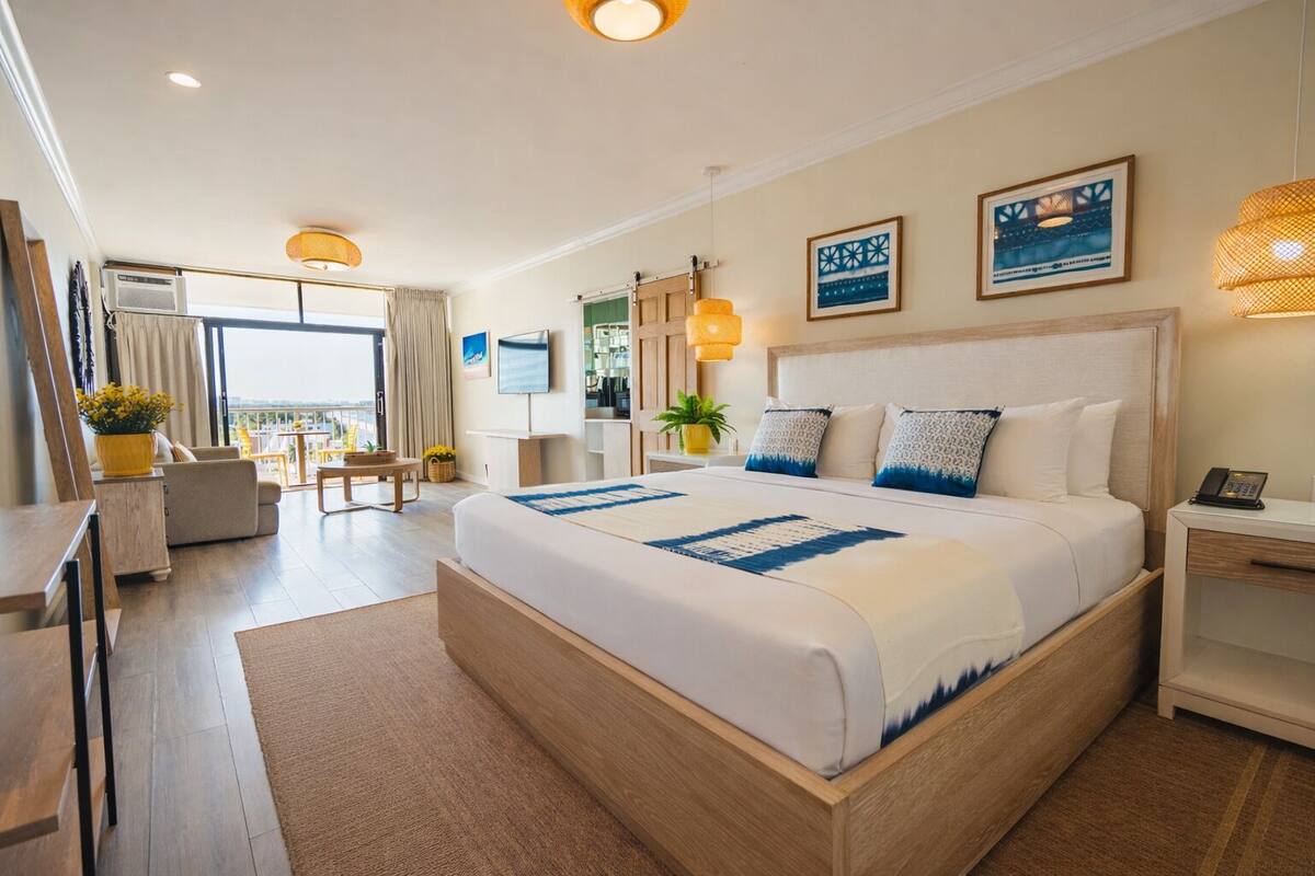 Una habitación de hotel moderna con una cama grande, un escritorio, una silla y un balcón con vistas.